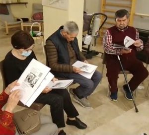Grupo de personas mayores sentadas en círculo leyendo un libro